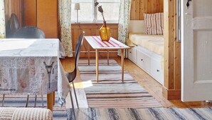 Una habitación acogedora con una cama, una mesa con un florero, una silla y una ventana con cortinas.