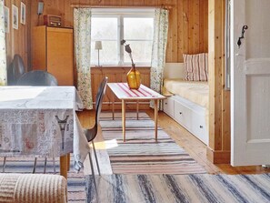 A cozy room with a bed, a table with a vase, a chair, and a window with curtains. - 6 Person Holiday Home in Vaxholm (Vaxholm)