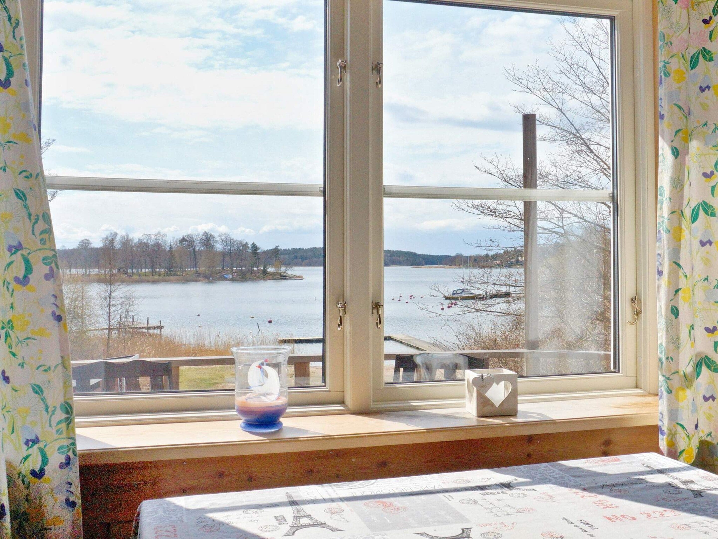 A room with a large window overlooking a lake, a wooden bench, and a table with a map.