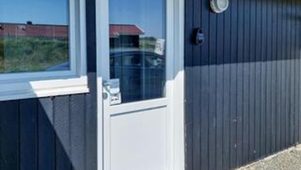 A building with a window, a door, and a small circular object on the wall. - 8 Person Holiday Home in Blavand (Blavand)