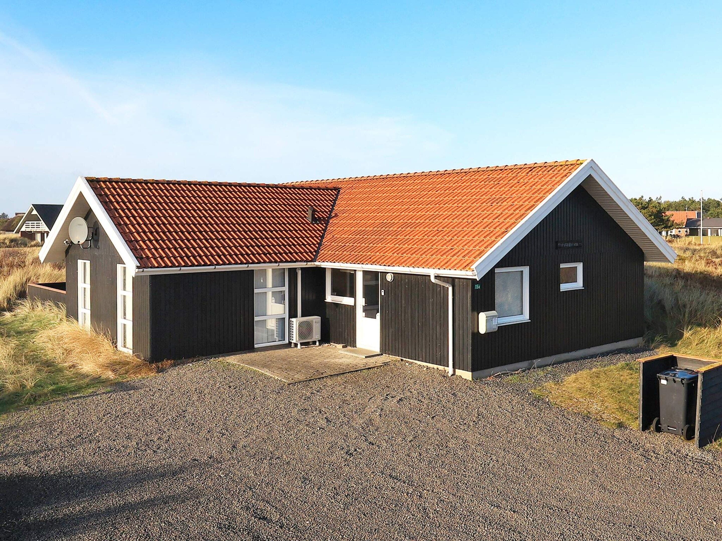 A two-story building with a sloped roof, a front porch, and a gravel driveway.