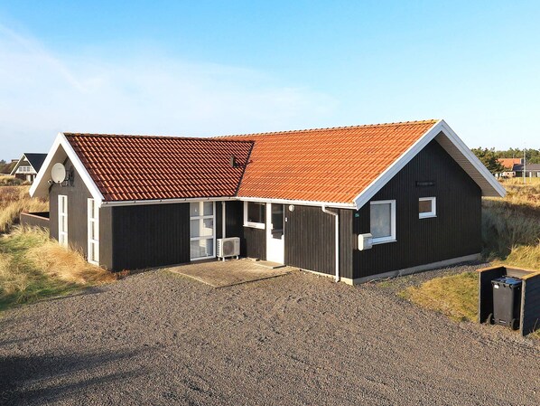 Un bâtiment à deux étages, doté d’un toit en pente, d’un porche à l’avant et d’une allée gravillonnée.