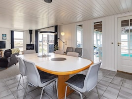 A modern living room with a round dining table, grey chairs, a sofa, and a fireplace.