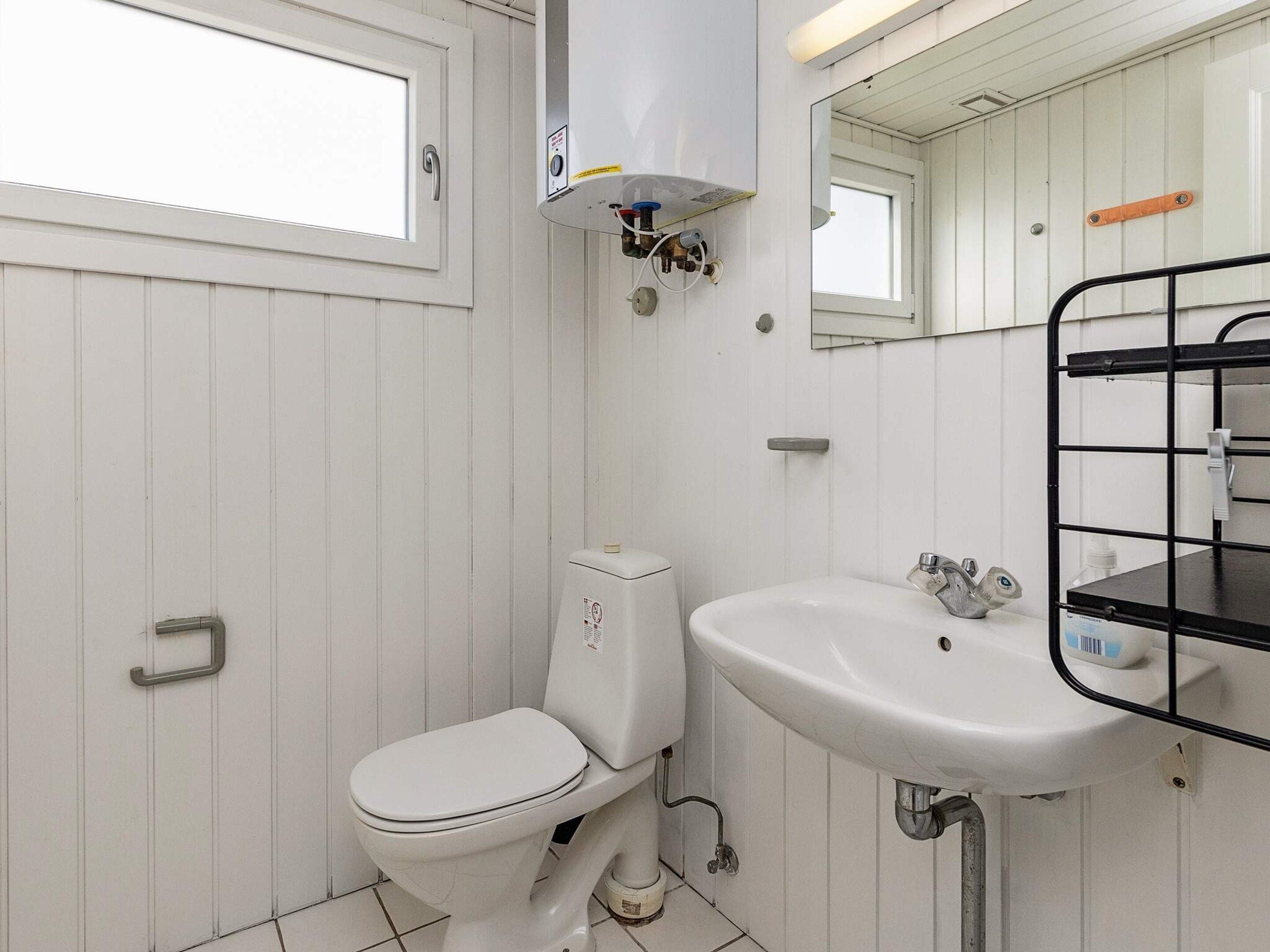 A small, white bathroom with a toilet, sink, and mirror.