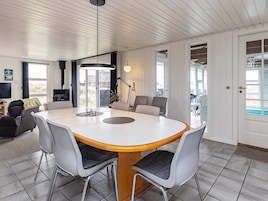 A modern dining area with a round table, grey chairs, and a wooden table base.