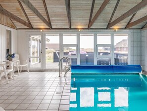 Une piscine intérieure avec un sol carrelé et un banc.