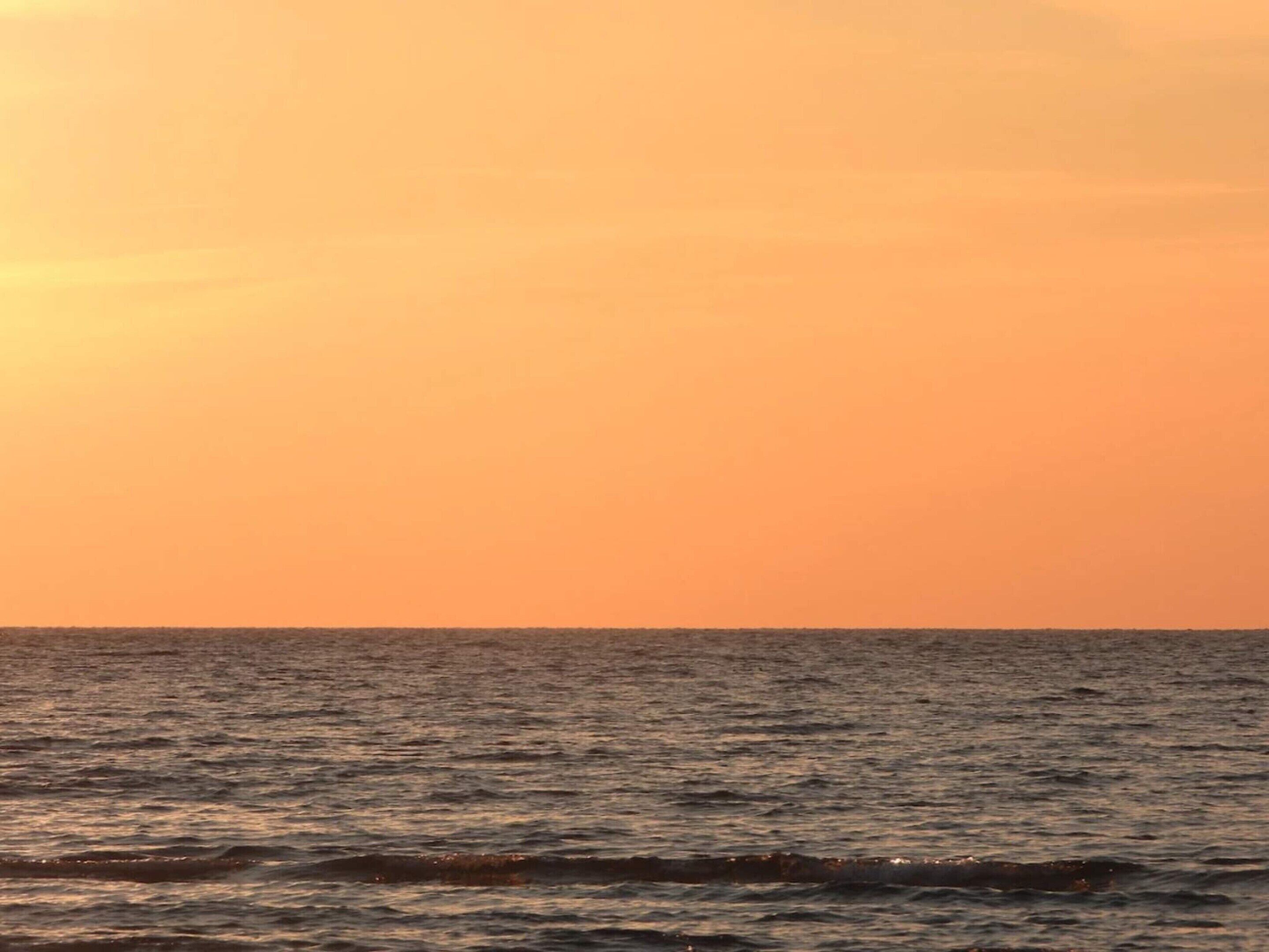 A sunset over a calm sea with no visible land or structures.