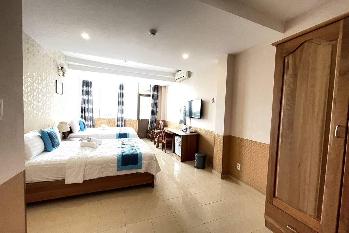 Una habitación de hotel con una cama, un escritorio, un televisor y un armario.