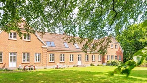 A two-story brick building with a sloped roof, multiple windows, and a well-maintained lawn. - 4 Star Holiday Home in Ulfborg (Ulfborg)