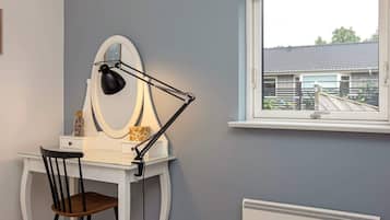 Una habitación con escritorio, silla y ventana con vista a una casa.