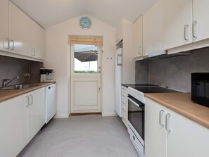 A compact kitchen with white cabinets, a stainless steel range, and a microwave.