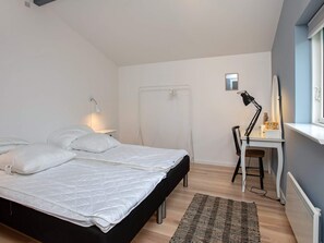 A bedroom with a bed, a desk, a chair, a radiator, and a window. - 6 Person Holiday Home in Vaeggerlose (Vaeggerlose)