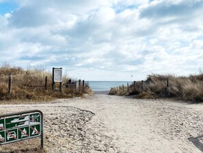 A sandy beach path leading to the sea with a signboard and a green informational sign. - 6 Person Holiday Home in Vaeggerlose (Vaeggerlose)