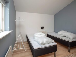 A bedroom with two beds, a bedside table, a lamp, and a drying rack.