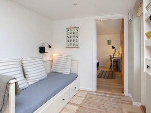 A room with a bed, a bedside lamp, a wall-mounted light, and a door leading to another room. - 6 Person Holiday Home in Vaeggerlose (Vaeggerlose)