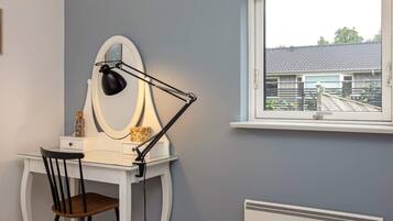 A room with a desk, chair, and a window with a view of a house.