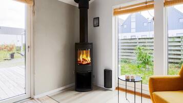 A modern interior with a wood-burning stove, a glass door leading outside, and a view of a backyard.