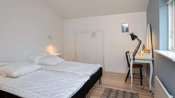 A bedroom with a bed, a desk, a chair, a radiator, and a window.