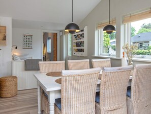 A dining area with wicker chairs, a white table, and pendant lights. - 6 Person Holiday Home in Vaeggerlose (Vaeggerlose)