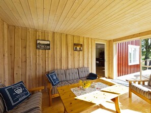 A wooden interior with a sofa, a table with a vase, and a view through a door. - 4 Star Holiday Home in Bralanda (Bralanda)