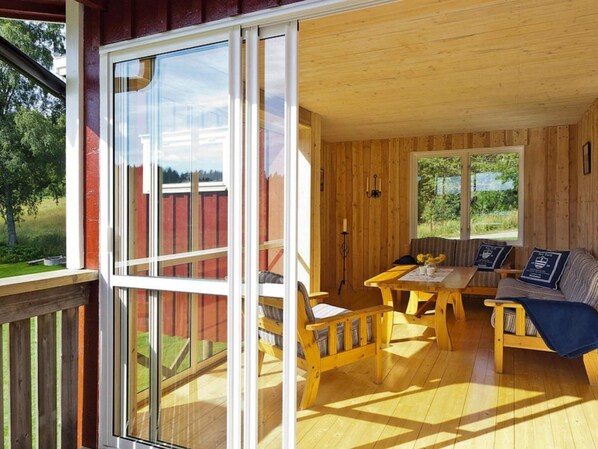 A wooden cabin with a deck, a sofa, a table, and chairs.