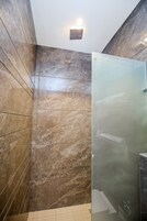 Un baño moderno con paredes de mármol y cabina de ducha de vidrio.