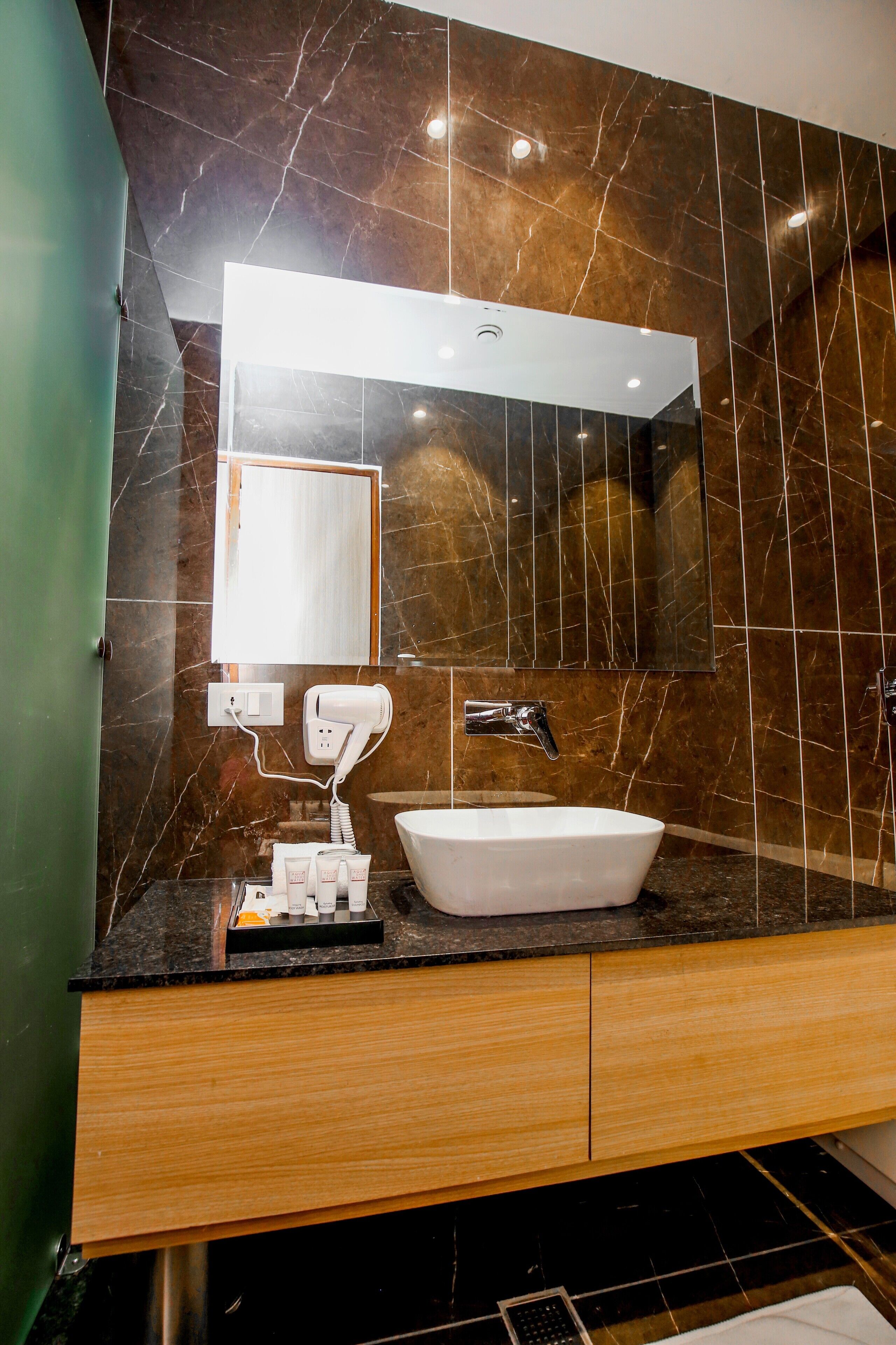 A bathroom with a marble wall, a white sink, a mirror, and a hairdryer.