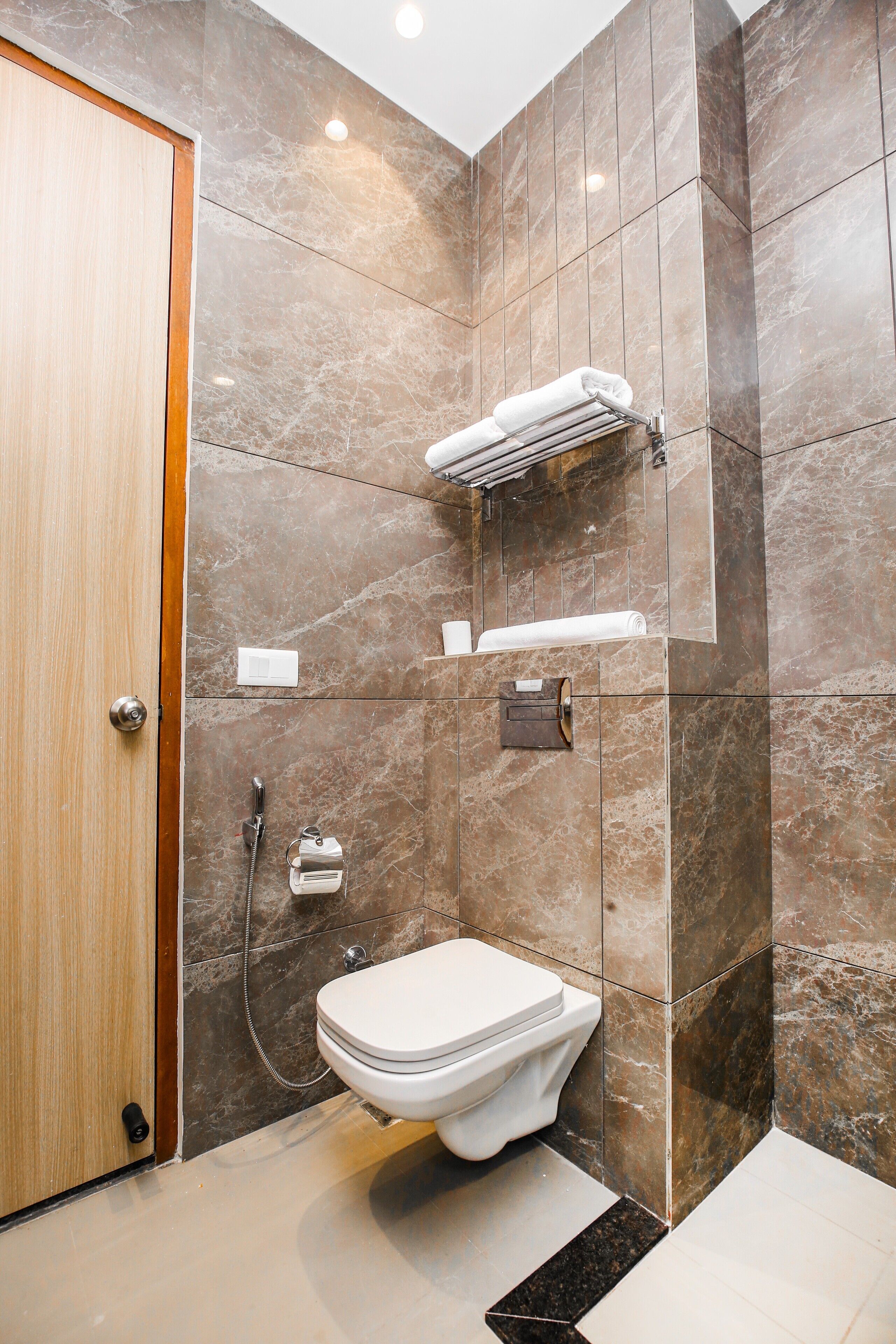 A modern bathroom with a toilet, a shower, and a towel rack.