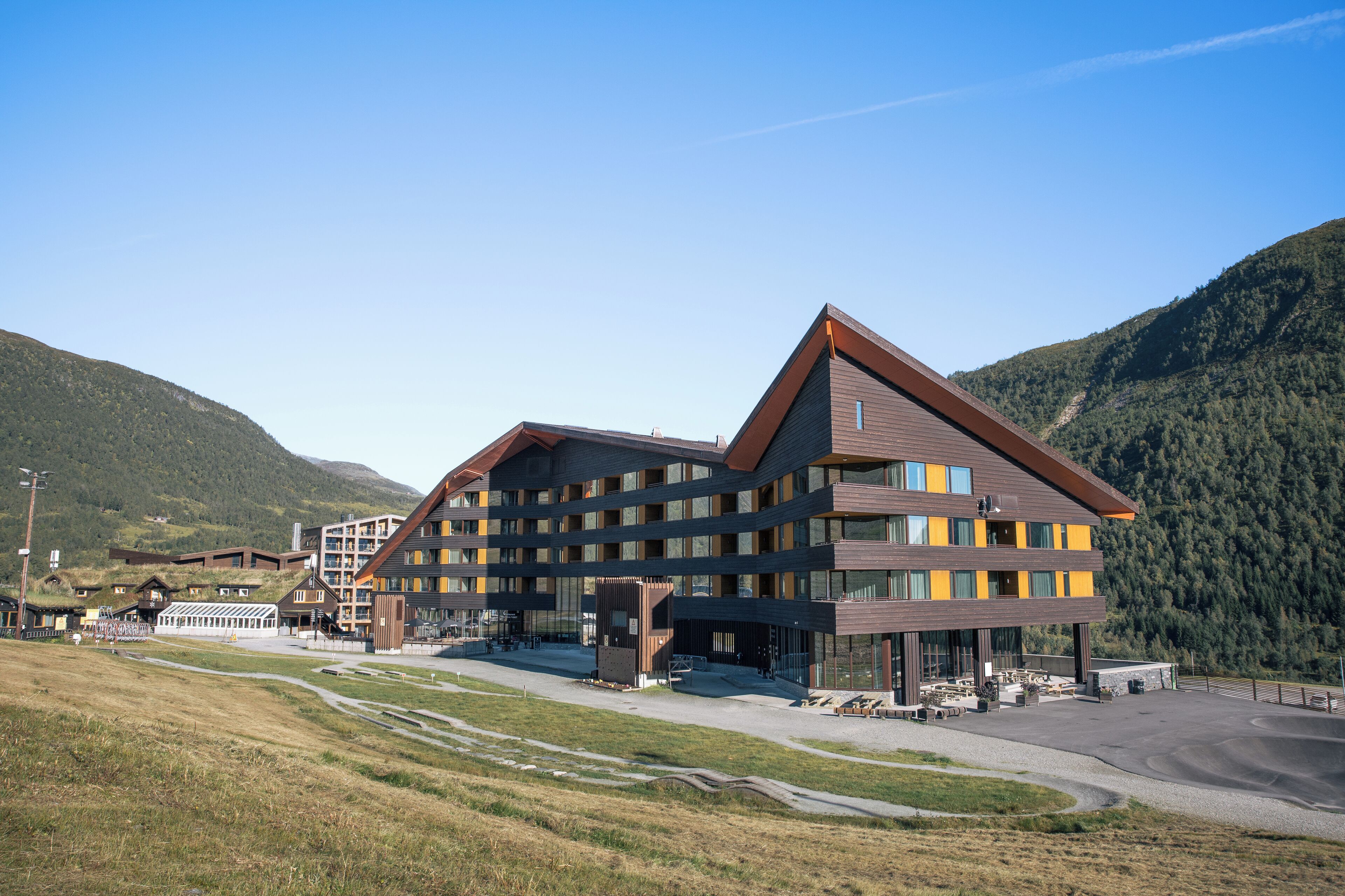 A modern hotel with multiple floors, a prominent entrance, and a parking area.