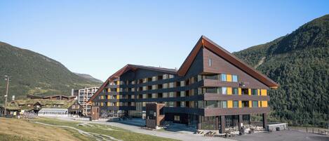 A modern hotel with multiple floors, a prominent entrance, and a parking area.