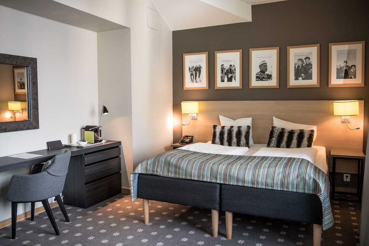 Ein Hotelzimmer mit Bett, Schreibtisch, Stuhl und Wandlampen.