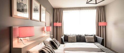 A hotel room with a large bed, two bedside lamps, a headboard, and a window with curtains.