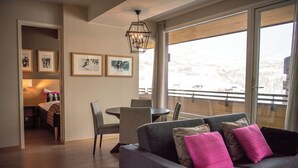 A modern living room with a sofa, chairs, a dining table, and artwork on the walls.