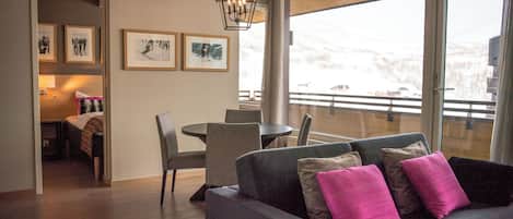 Un salon moderne avec un canapé, des fauteuils, une table à manger et des œuvres d’art accrochées aux murs.