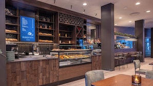 A modern restaurant with a wooden counter, a display menu, and a bar area.