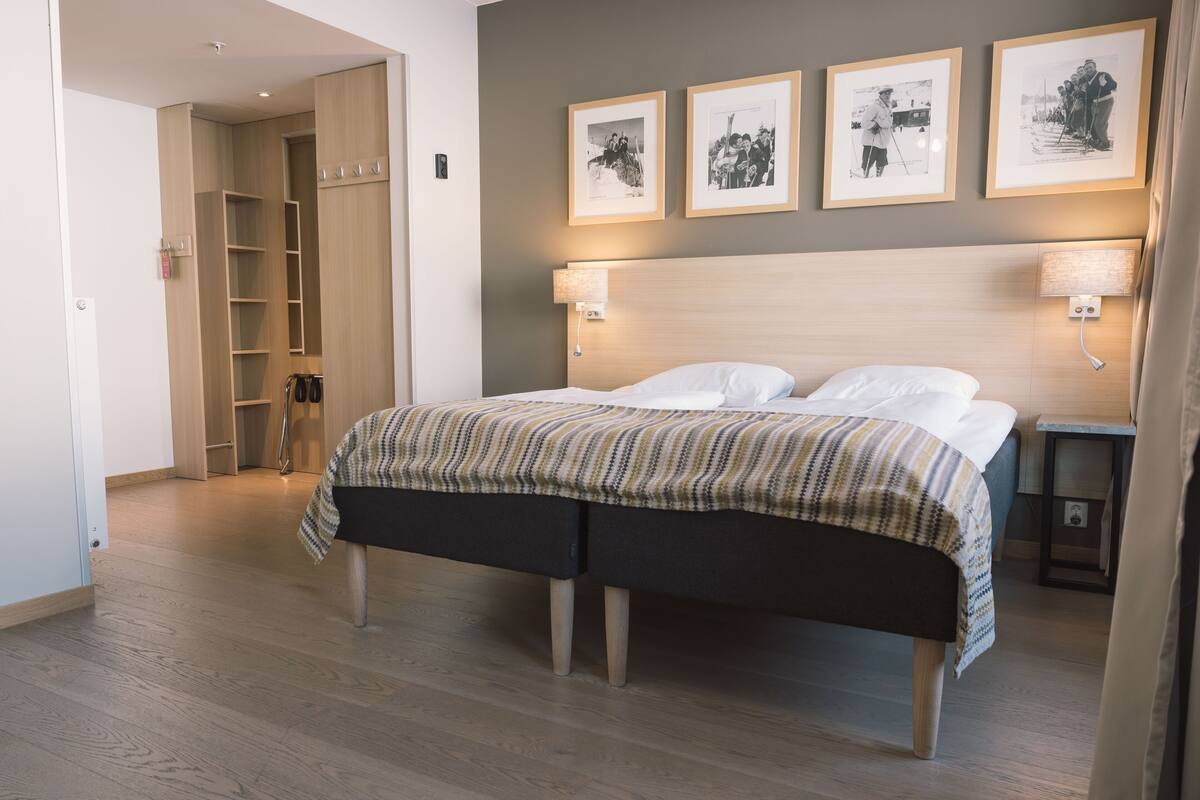 Ein Schlafzimmer mit Bett, Nachttischlampen, einem Kleiderschrank und gerahmten Bildern an der Wand.