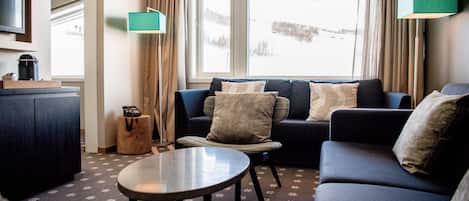 A cozy living room with a sofa, armchairs, a coffee table, and a TV.