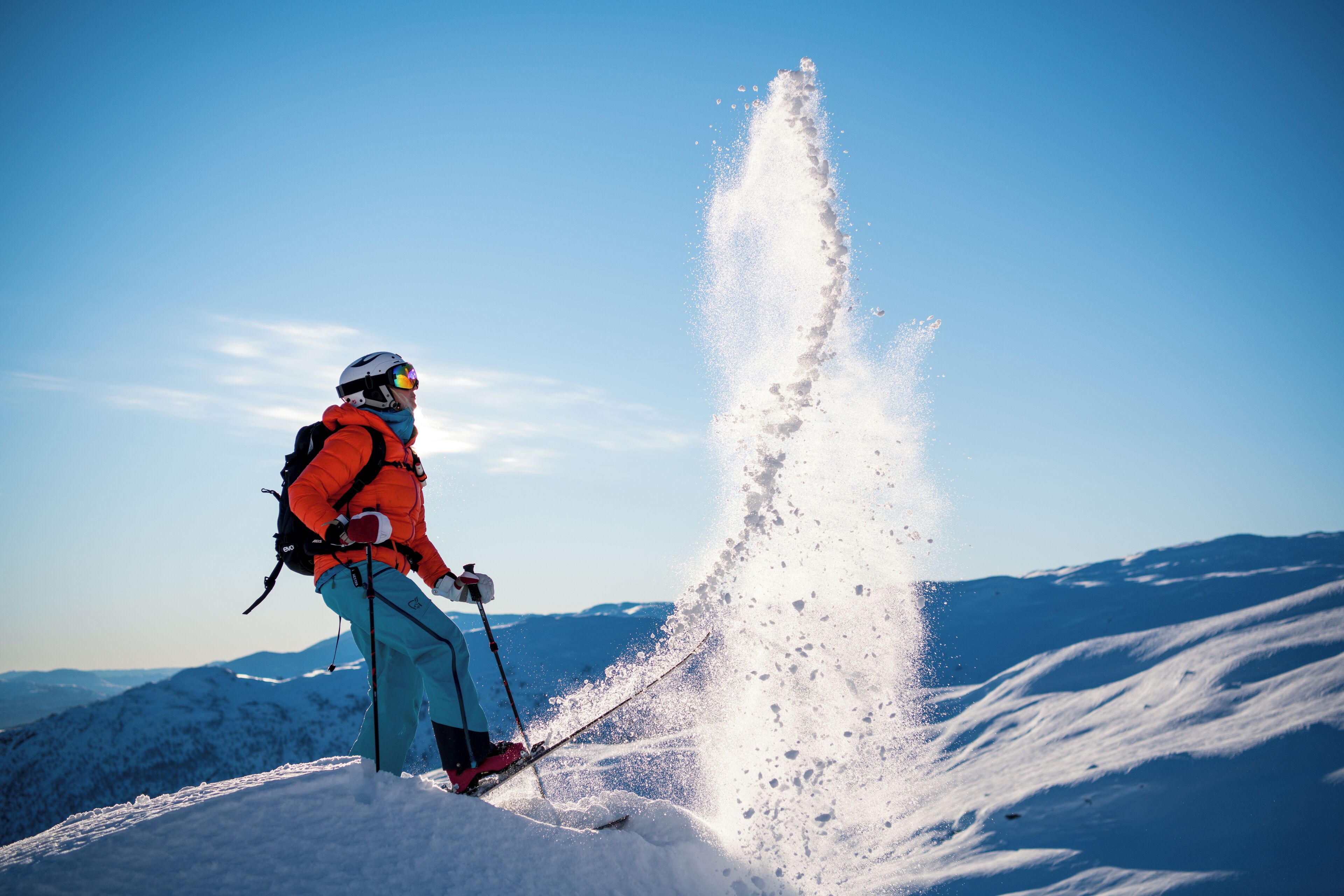 Une personne fait du ski sur une montagne enneigée, sous un ciel dégagé.