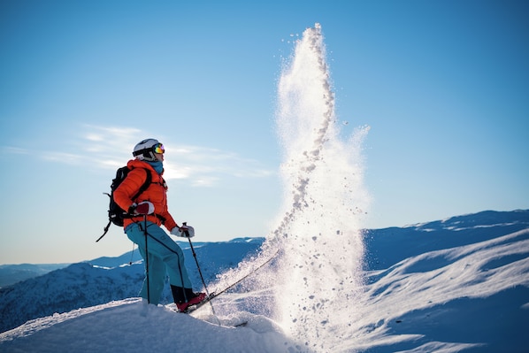 Una persona esquiando en una montaña nevada bajo un cielo despejado.