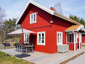 A red wooden house with a deck, white windows, and a covered outdoor seating area. - 4 Star Holiday Home in Grebbestad (Grebbestad)
