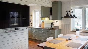 A modern kitchen with a built-in stove, grey cabinets, and a dining area with a wooden table and chairs.