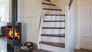A staircase with wooden steps and a black wood-burning stove with visible flames. - 4 Star Holiday Home in Grebbestad (Grebbestad)