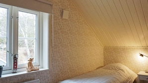 A bedroom with a bed, a window with a view, a radiator, and a nightstand with a lamp. - 4 Star Holiday Home in Grebbestad (Grebbestad)