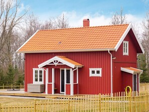 A red wooden building with a sloped roof, a porch with white trim, and a small chimney. - 4 Star Holiday Home in Grebbestad (Grebbestad)