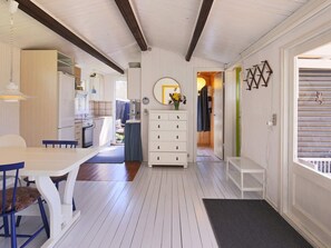 A compact kitchen with a dining area, a white dresser, and a view into another room. - 4 Person Holiday Home in Jaegerspris (Jægerspris)
