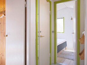 A narrow hallway with two doors, one leading to a room with a bed and a window. - 4 Person Holiday Home in Jaegerspris (Jægerspris)