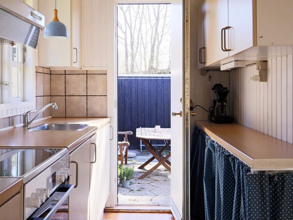 A compact kitchen with a sink, a coffee machine, and a view of an outdoor seating area.
