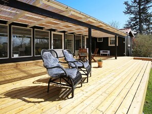 A wooden deck with outdoor seating and a covered area with large windows. - 4 Person Holiday Home in Jaegerspris (Jægerspris)