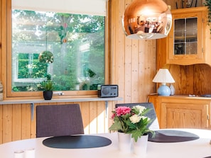 A modern kitchen with wooden cabinets, a large window with a view of greenery, a radio, and a table with a vase of flowers. - 4 Person Holiday Home in Allingabro (Allingåbro)