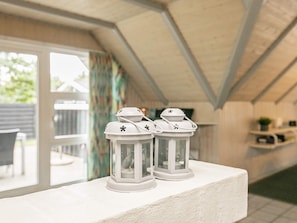 A room with a white ceiling, a window with curtains, and two white lanterns on a white ledge.
